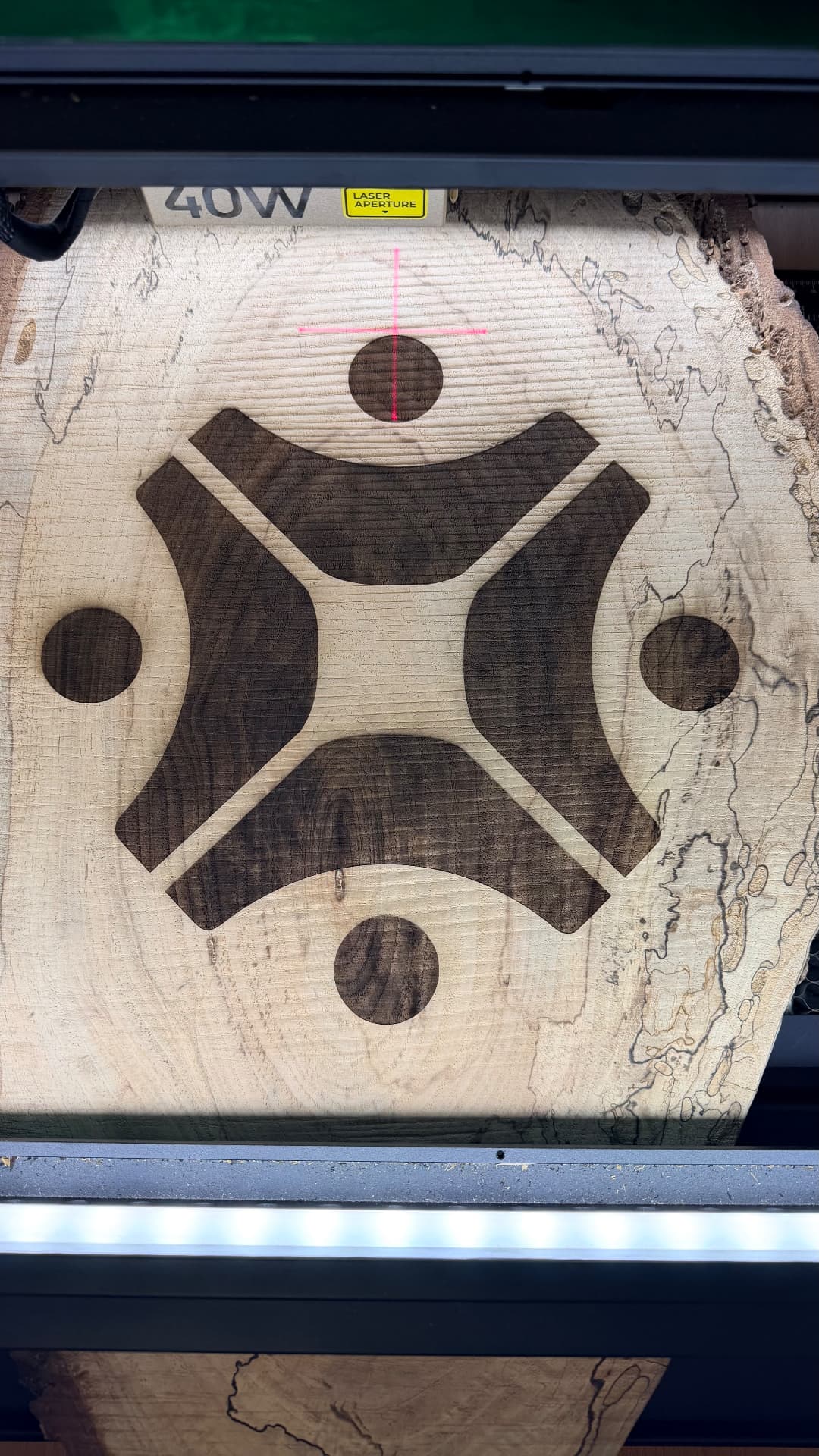 Logo engraving in progress on a maple slab